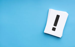 青い背景に置かれた！マークの紙