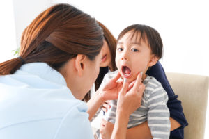 口を大きく開けて歯を見せる男の子